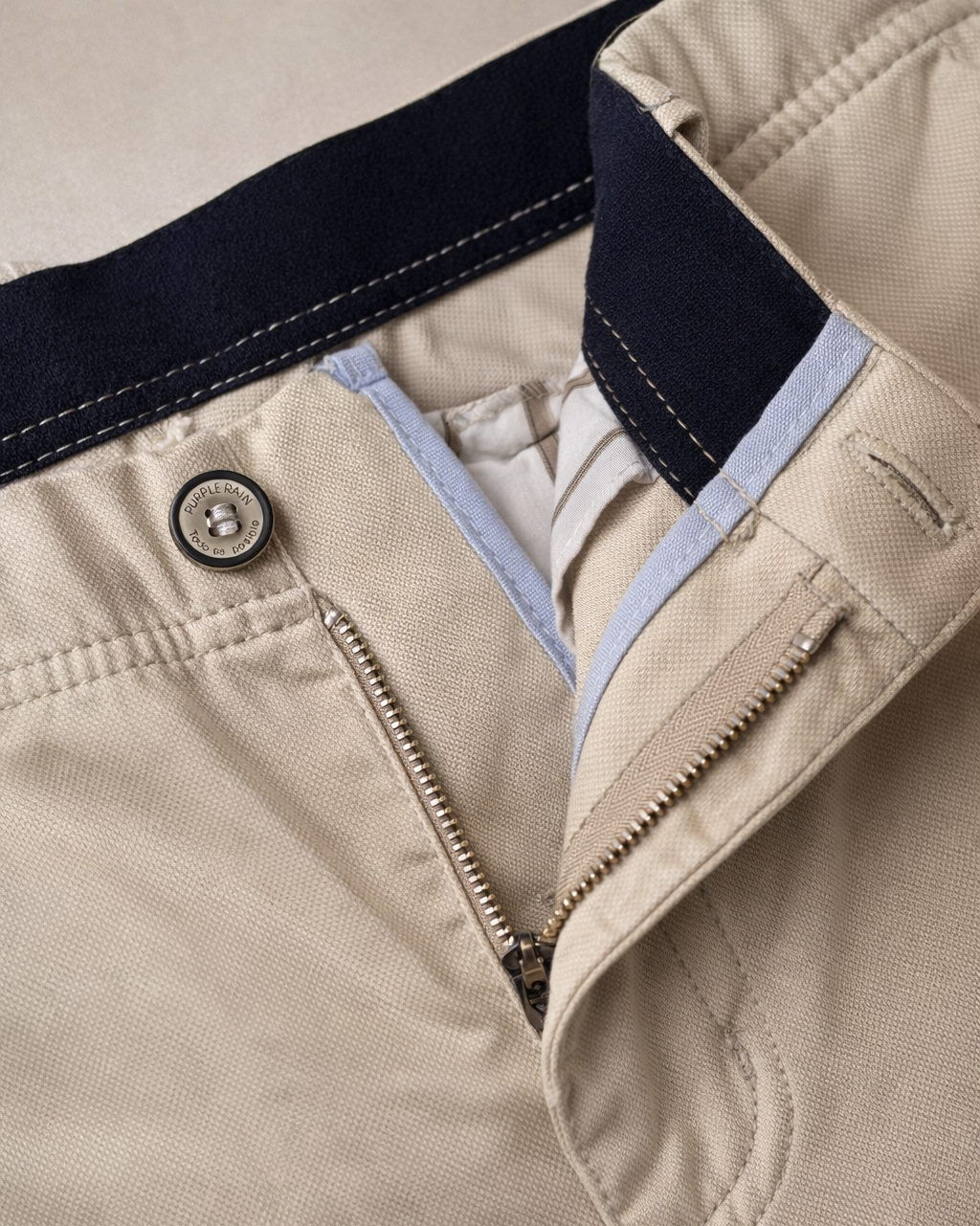 "Pantalón masculino color caramelo en drill texturizado tipo micropunto, vista posterior en primer plano. Diseño slim fit con bolsillos traseros ribeteados, botón decorativo, cremallera lateral discreta y marquilla Purple Rain en la pretina. Acabados premium y textura refinada visible en la tela."