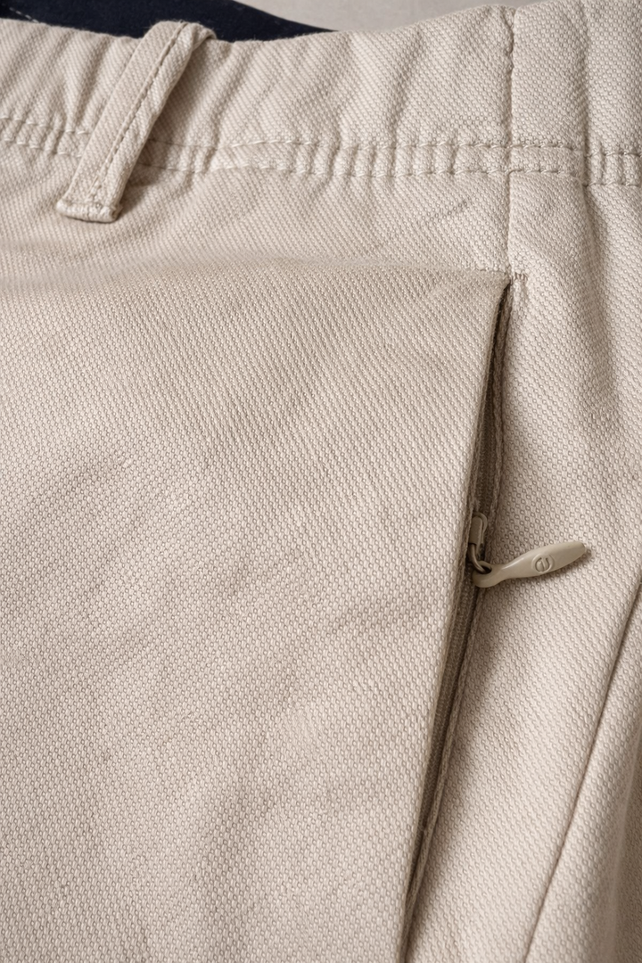 "Pantalón masculino color caramelo en drill texturizado tipo micropunto, vista posterior en primer plano. Diseño slim fit con bolsillos traseros ribeteados, botón decorativo, cremallera lateral discreta y marquilla Purple Rain en la pretina. Acabados premium y textura refinada visible en la tela."
