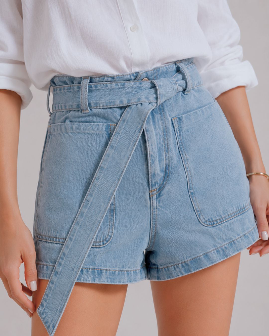 Short denim azul claro para mujer con tiro alto y cinturón elaborado en la misma tela. Diseño femenino que estiliza la silueta y aporta comodidad para el día a día. bolsillos de parche 